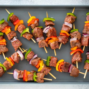 Place marinated meat, bell pepper, and red onion on skewers.